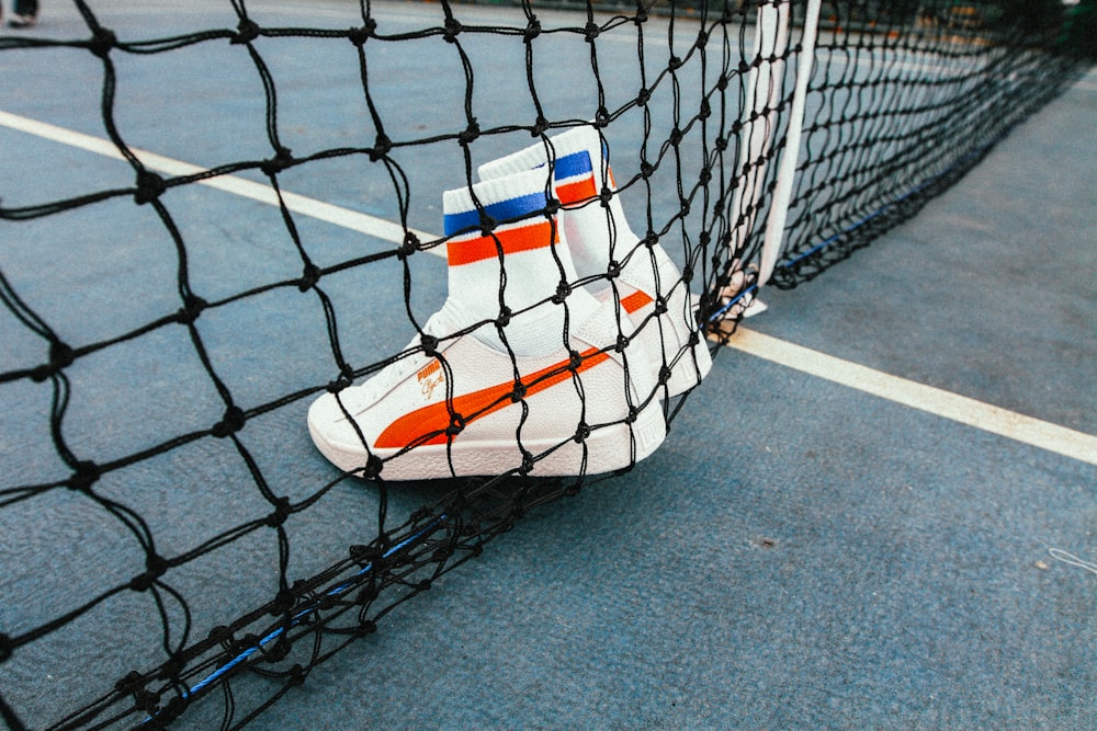white-and-red Puma Sock shoes on tennis net