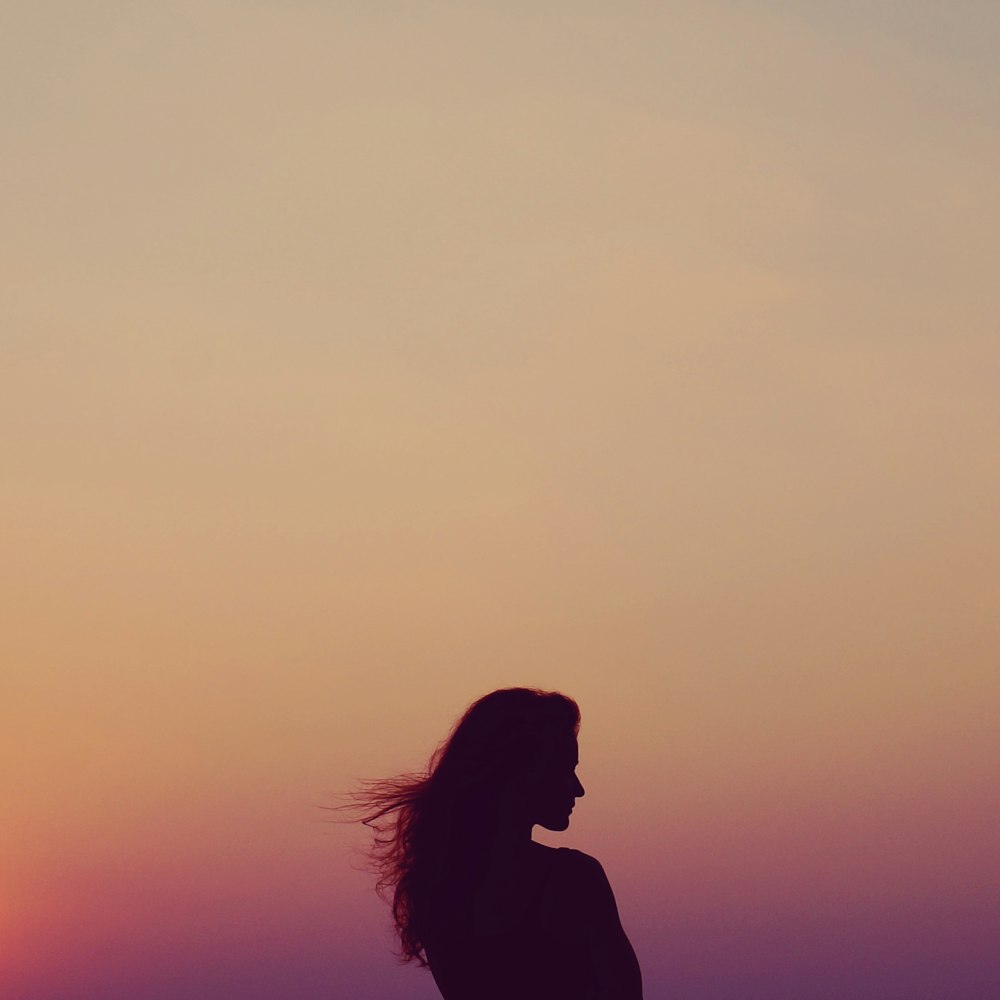 Silueta de mujer bajo cielo naranja