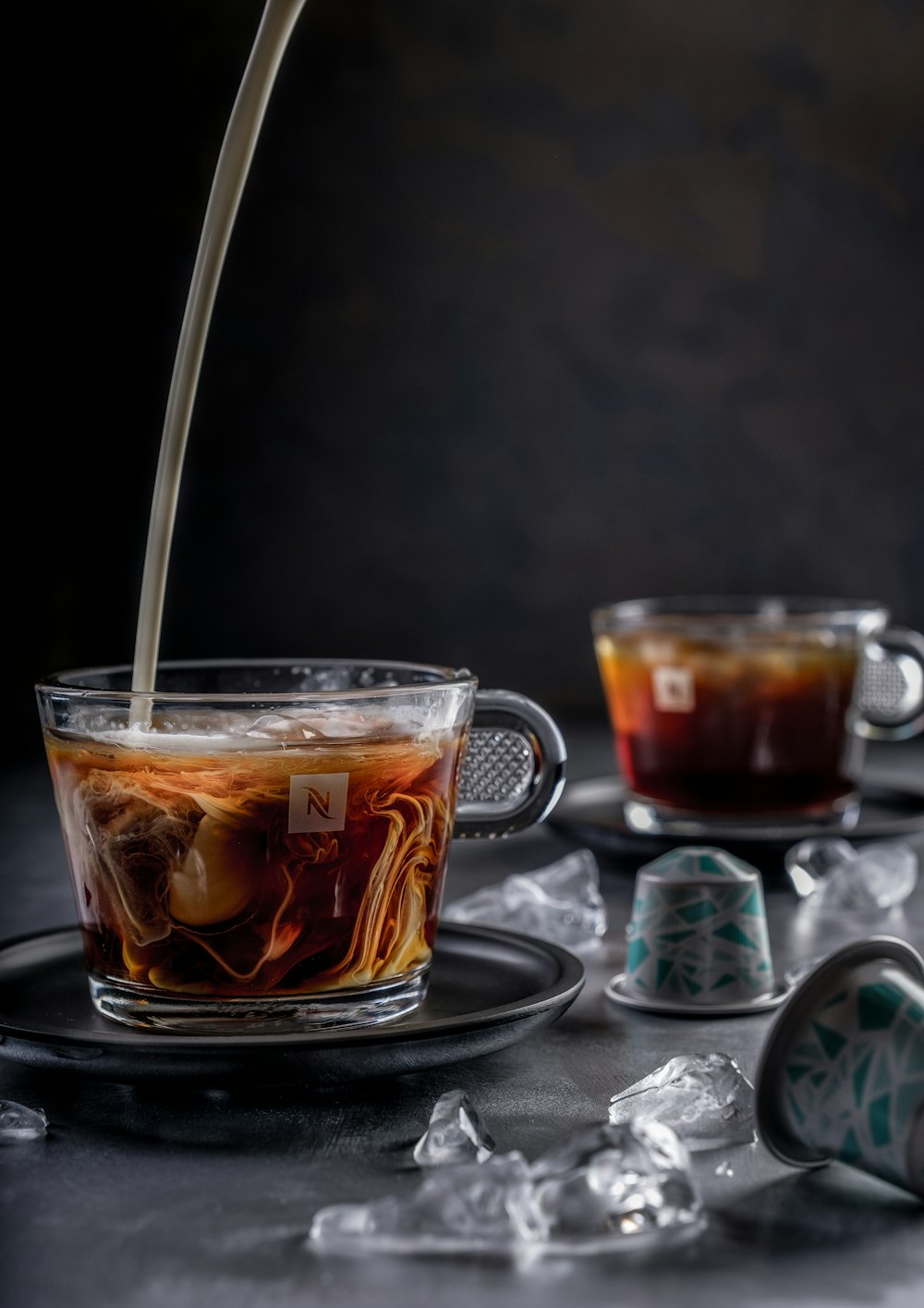 personne versant un liquide brun dans une tasse en verre transparent