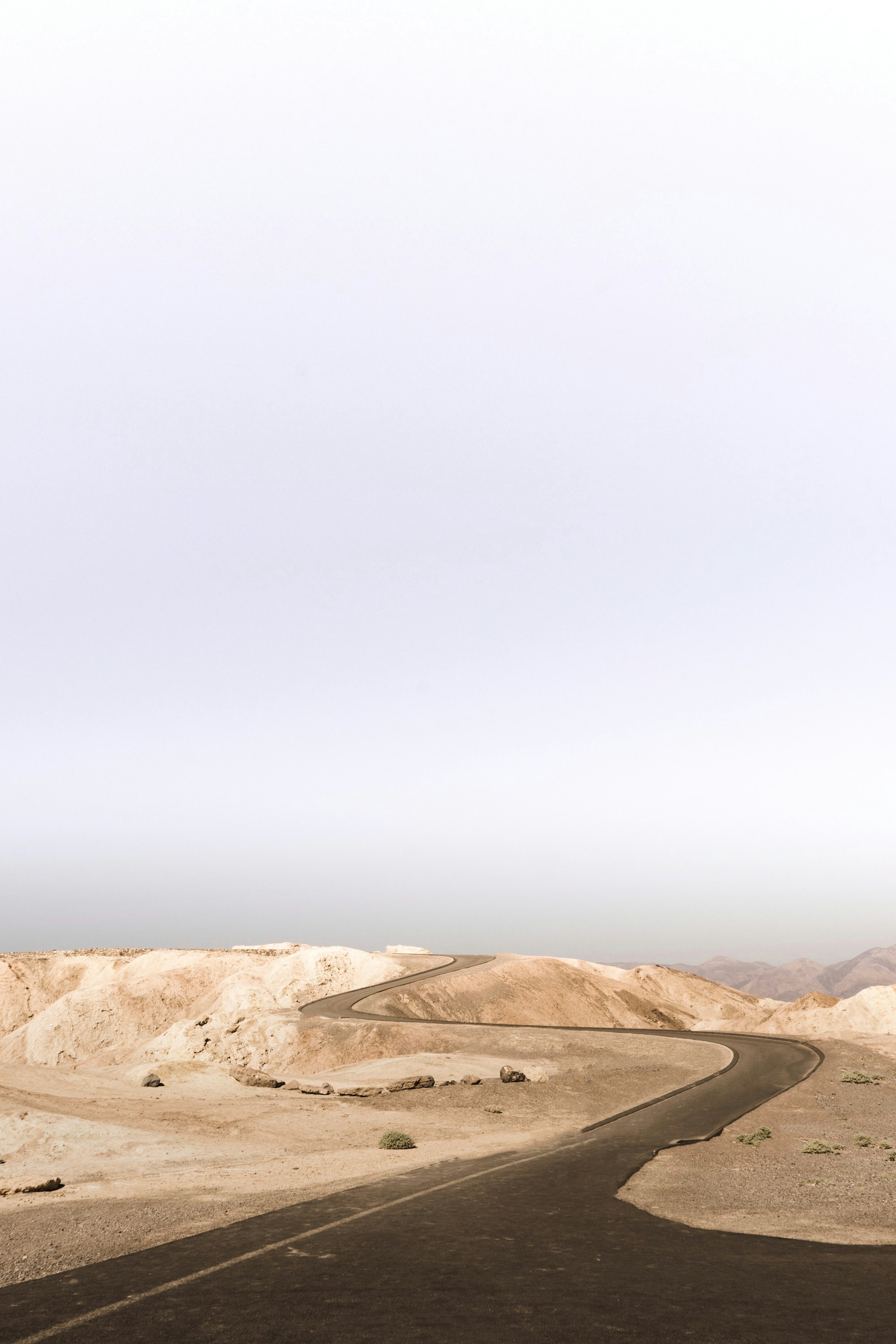 grey asphalt road on desert during daytime