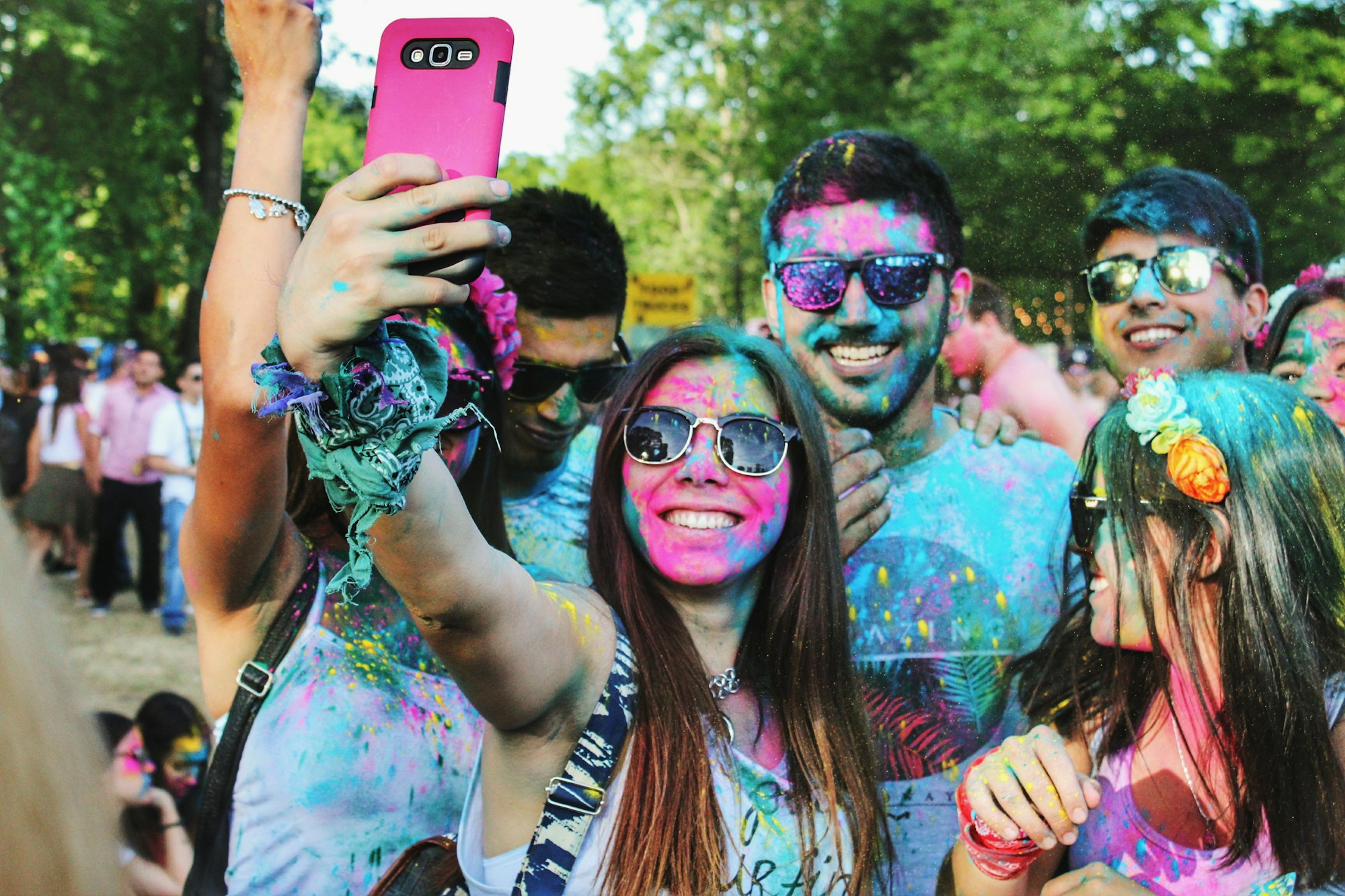 Kompisar med färger i ansiktet och på kläderna tar en selfie.