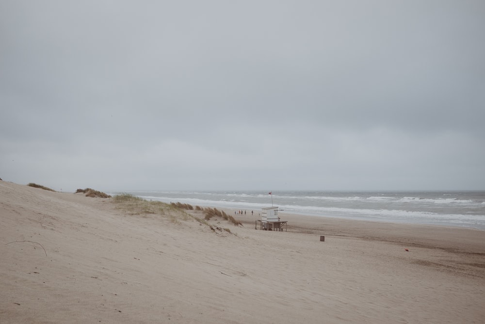 white life guard tower near sea under gray sky