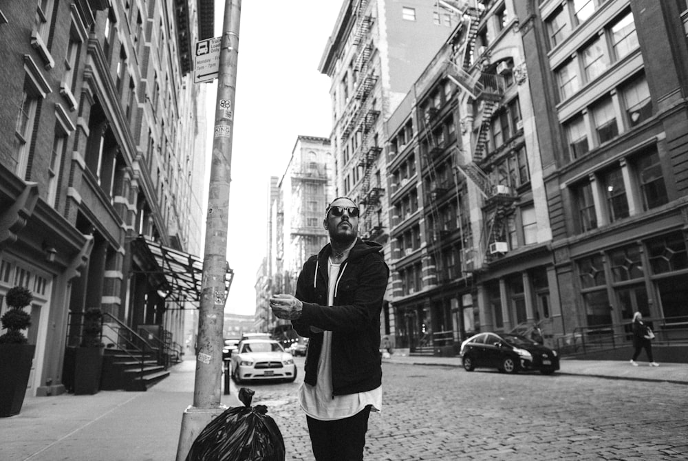 man standing beside the pole near the street