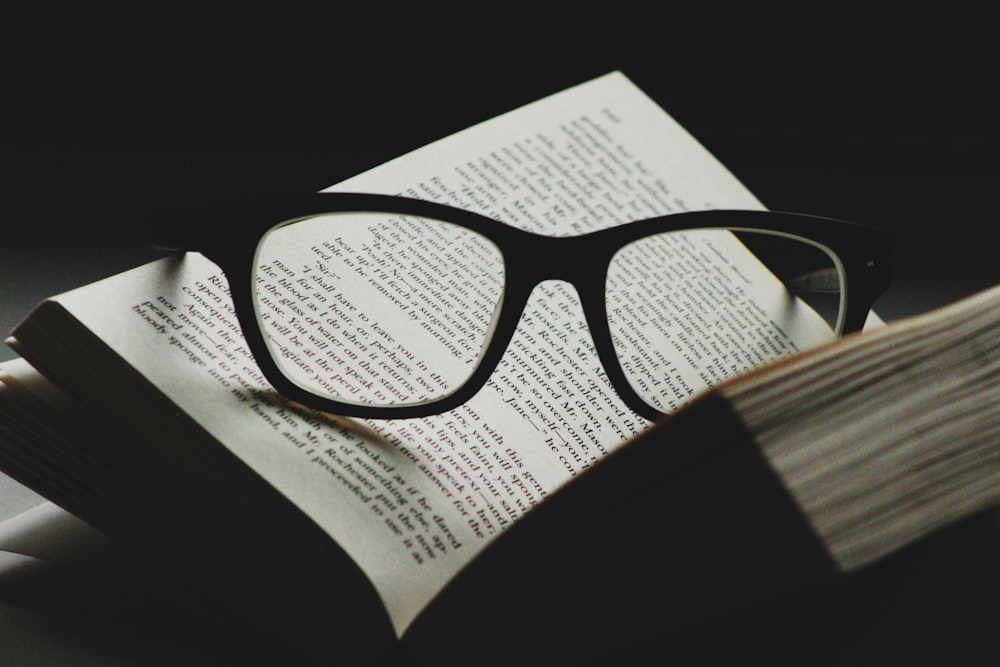 lunettes à monture noire sur le dessus d’un livre ouvert