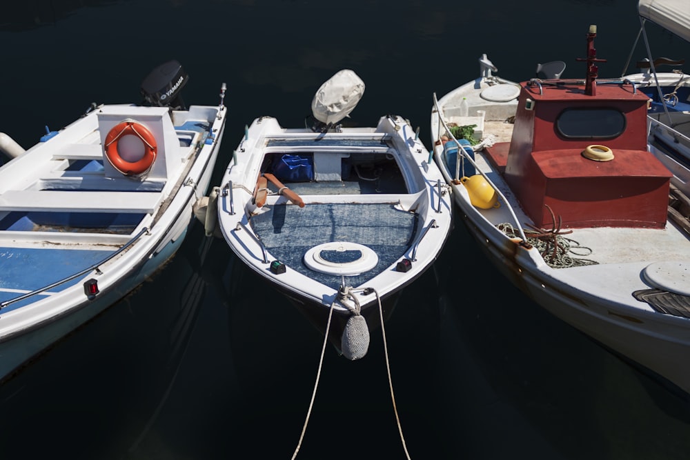 three assorted boats dock in a pier