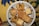 A decorative plate holds various pieces of baklava and other Middle Eastern pastries, with a detailed and colorful fabric underneath.