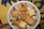 A decorative plate holds various pieces of baklava and other Middle Eastern pastries, with a detailed and colorful fabric underneath.
