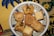 A decorative plate holds various pieces of baklava and other Middle Eastern pastries, with a detailed and colorful fabric underneath.
