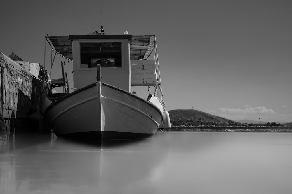 Fotografía en escala de grises de un barco cerca del muelle