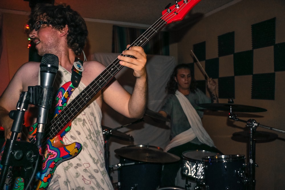 man playing guitar wearing one-shoulder dress inside room