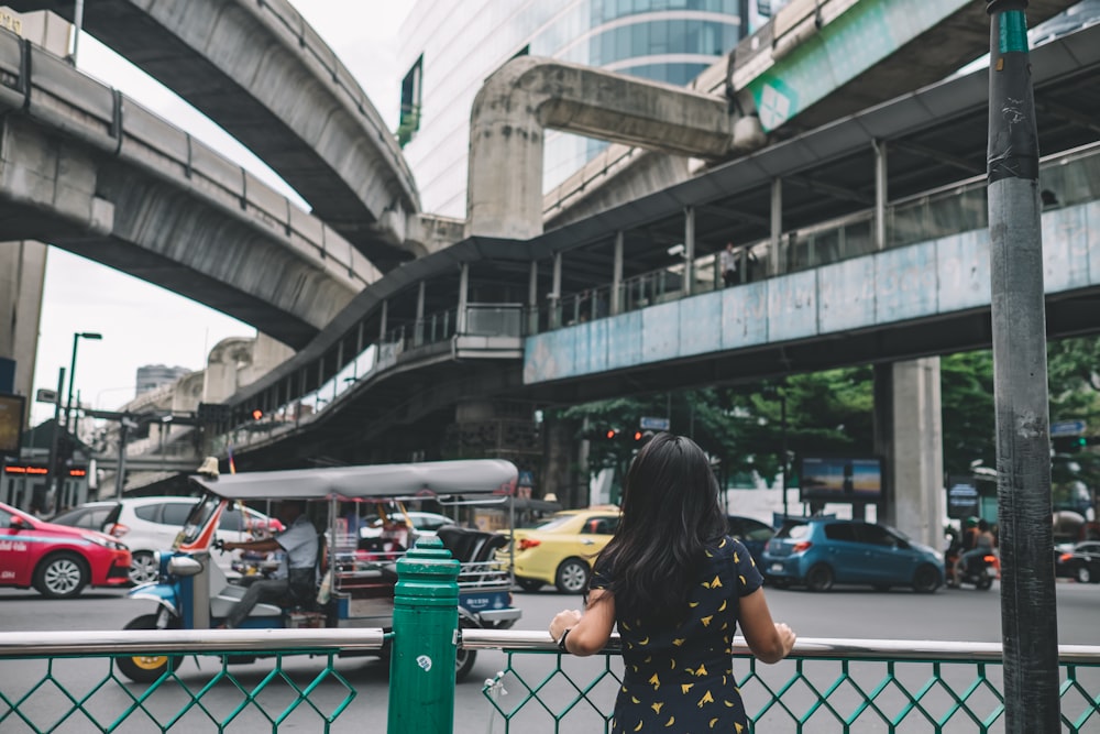 woman holding on road rails beside vehicle passing through