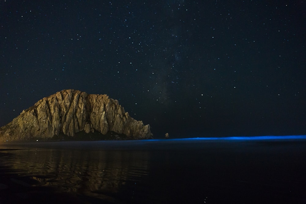 gray rock formation near sea at nighttime