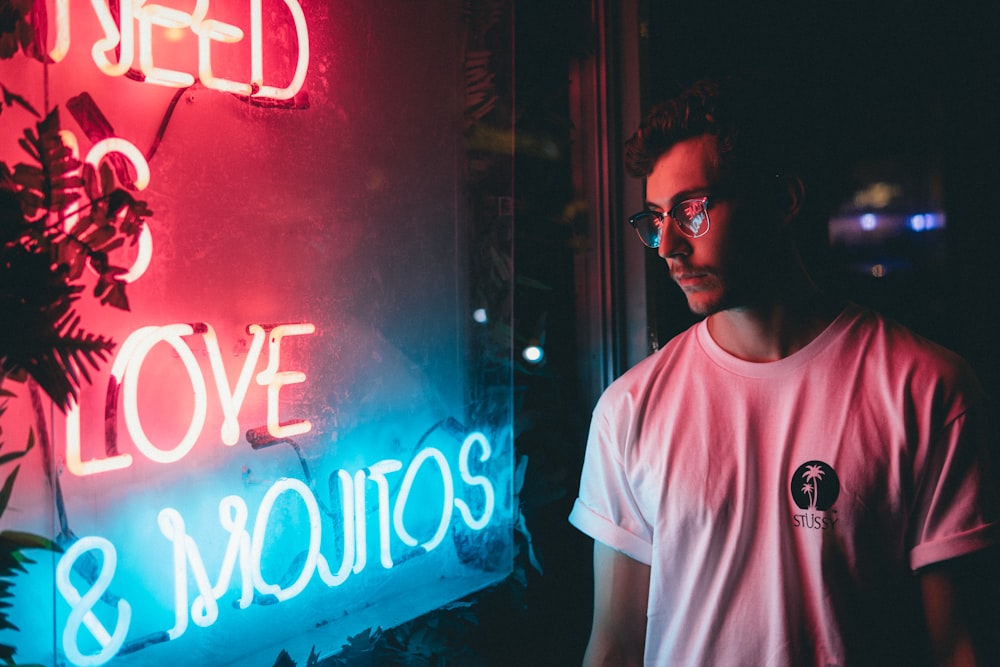 man standing near red and blue neon signage