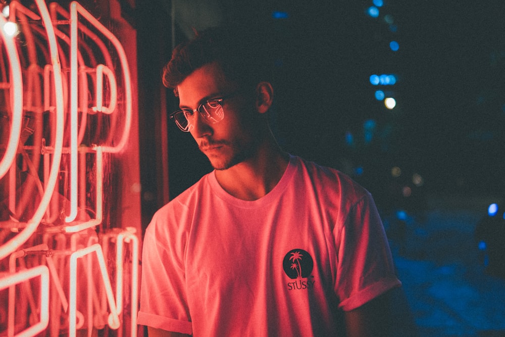 분홍색 네온 불빛 간판 앞에 서 있는 남자