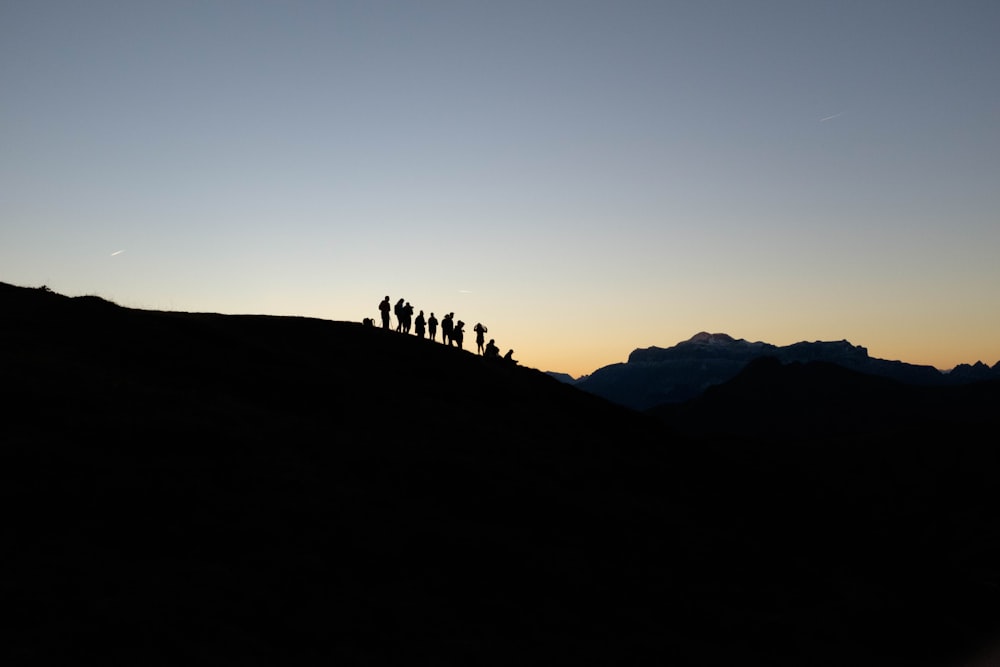 silueta de personas de pie en el borde de la montaña