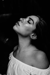 grayscale photo of a woman wearing white off-shoulder shirt