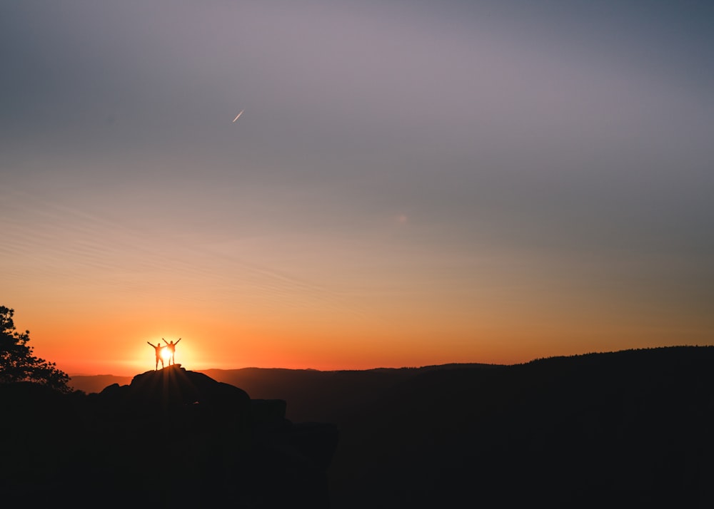 silhouette of couple on cliff during golden hour
