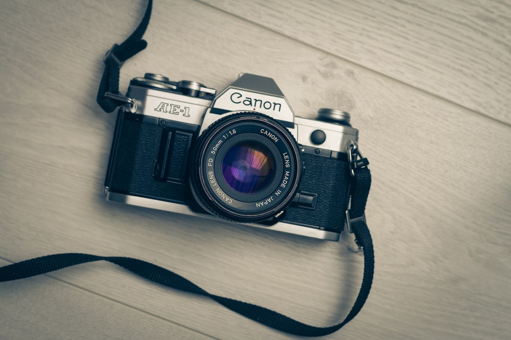 gray and black Canon AE-1 camera on wooden surface