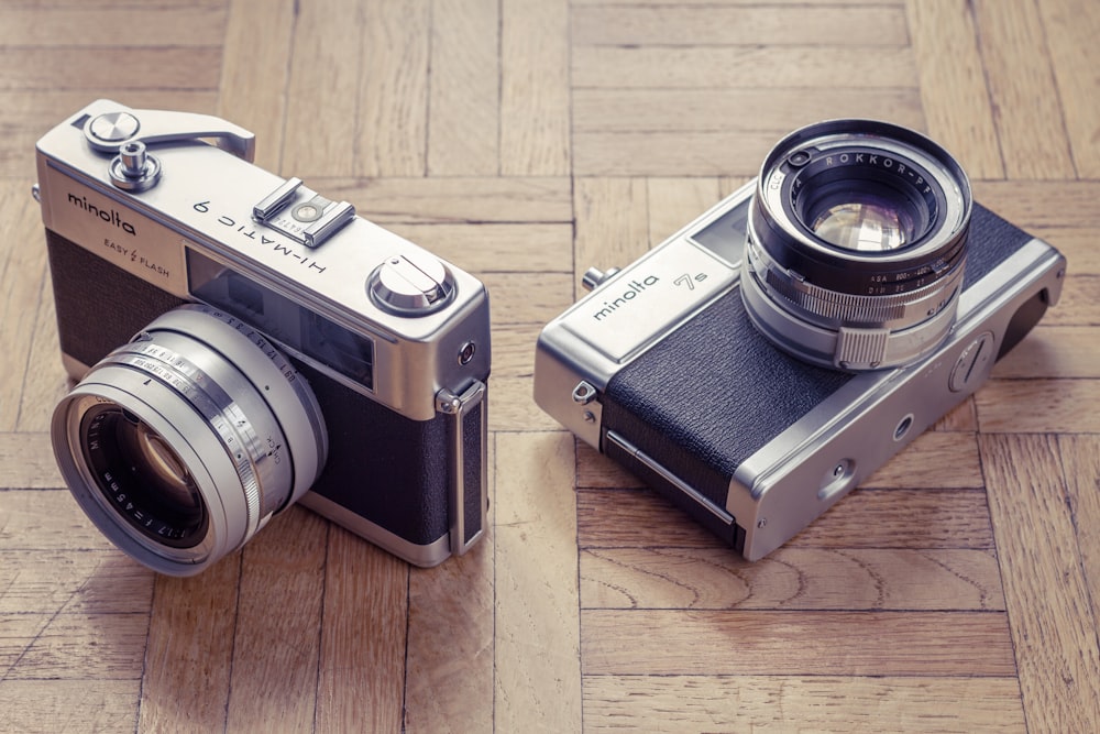 two gray film cameras on brown marble tiles