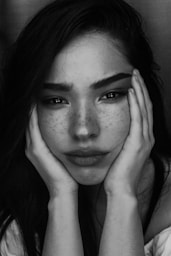 grayscale photography of woman with two hands on her face