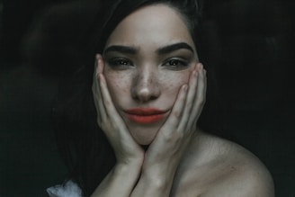 Artistic shot of a smiling woman showing subtle freckles on her nose and cheeks.