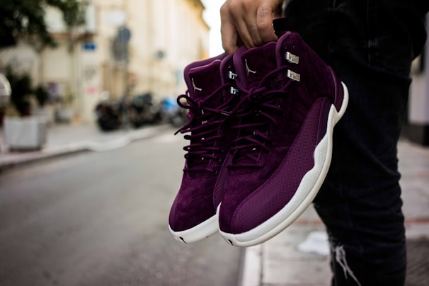 Close-up of vibrant purple sneakers with neon green accents on a gritty urban street background.