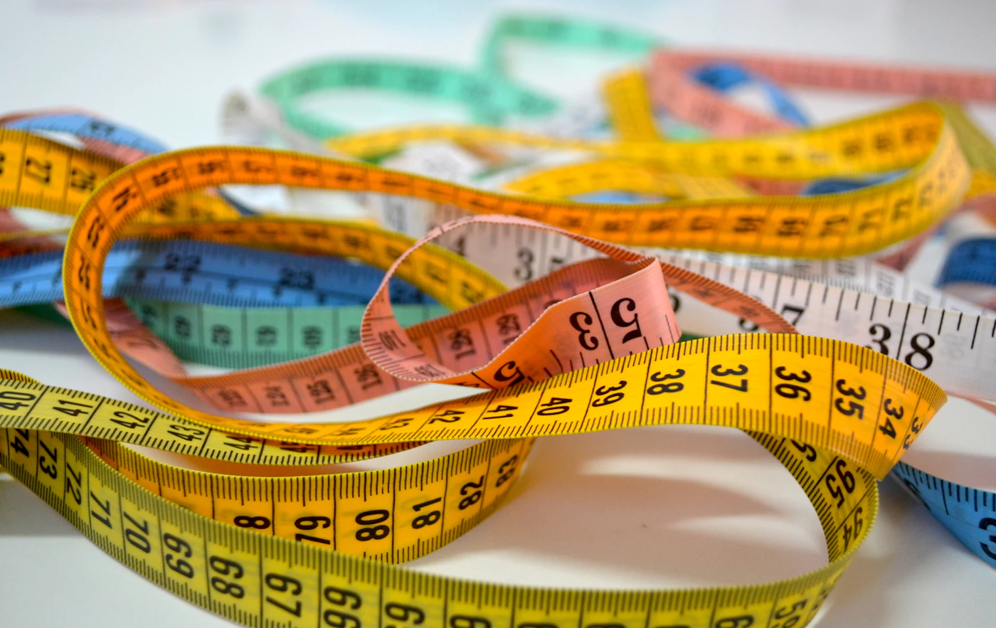 Assorted tape measures coiled together, symbolizing different methods of measuring the body