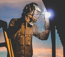 man on ladder welding post