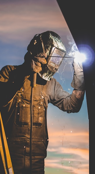 man on ladder welding post