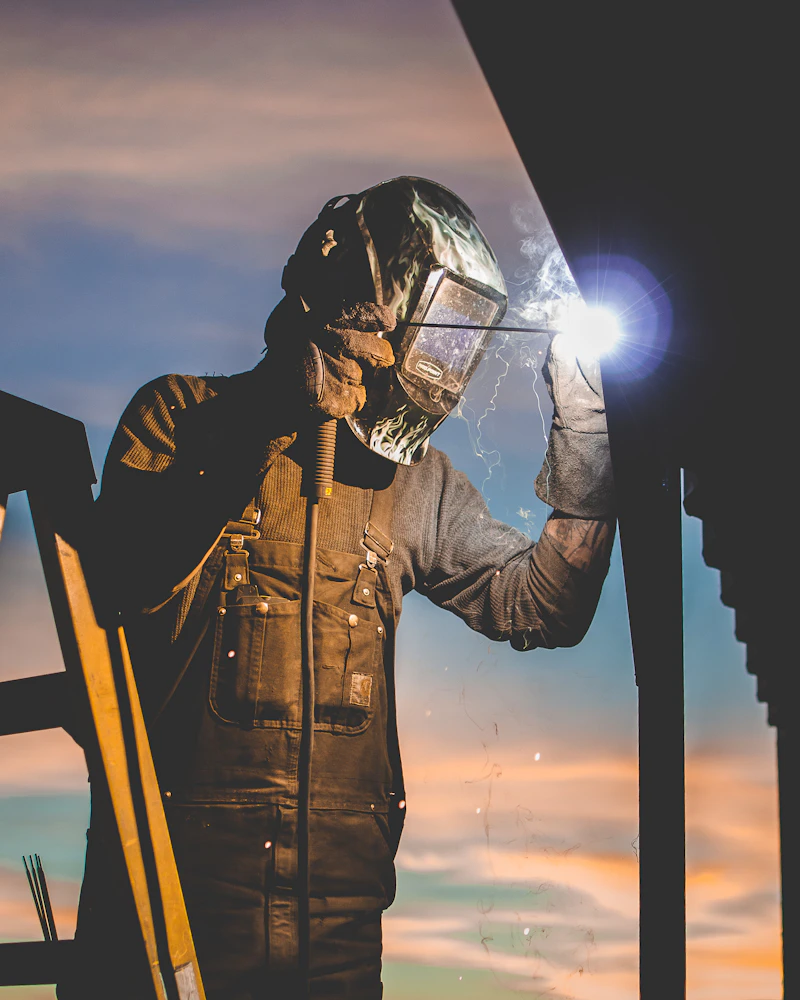 Industrial welder working at height with vivid sparks and flame