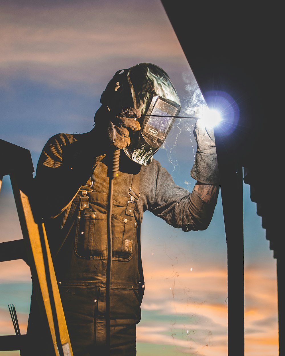 man on ladder welding post