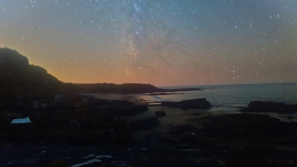 A serene dark academy style landscape with starry skies over an ocean at twilight.