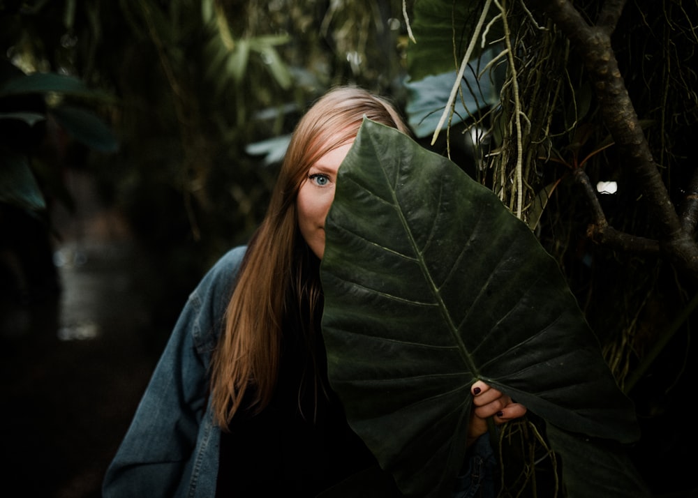 Femme debout tout en se couvrant le visage avec une feuille de taro