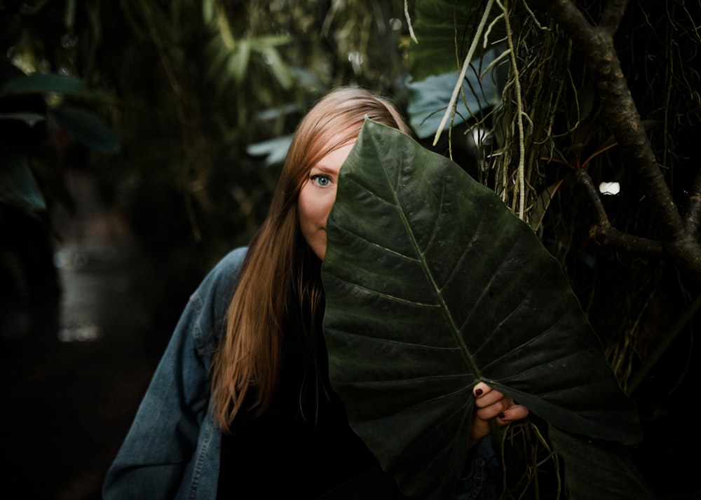 woman standing while covering her face with taro leaf