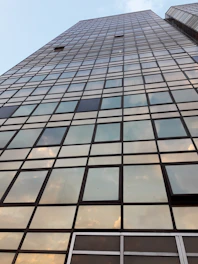 A towering commercial skyscraper with reflective glass and gold highlights at sunset.