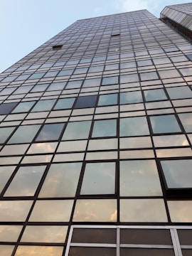 A towering glass skyscraper reflecting the city skyline at sunset.