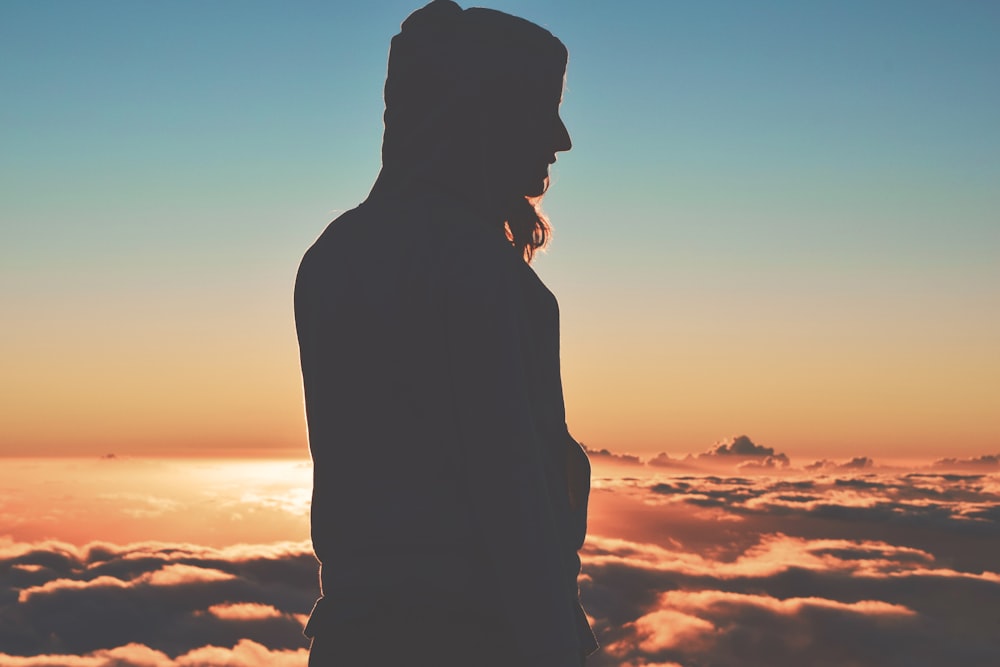 silhouette of person wearing hoodie on clouds
