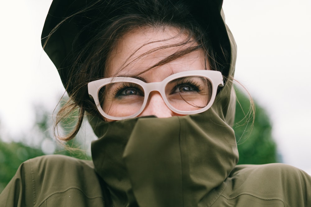 woman covering mouth with green turtleneck top