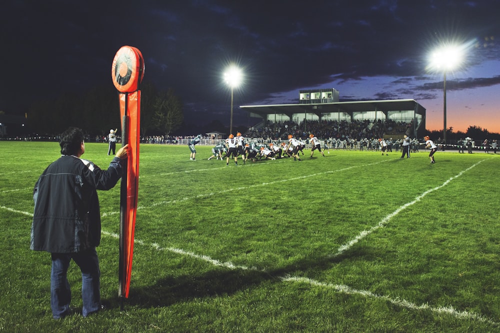 man holding football field post on side of field