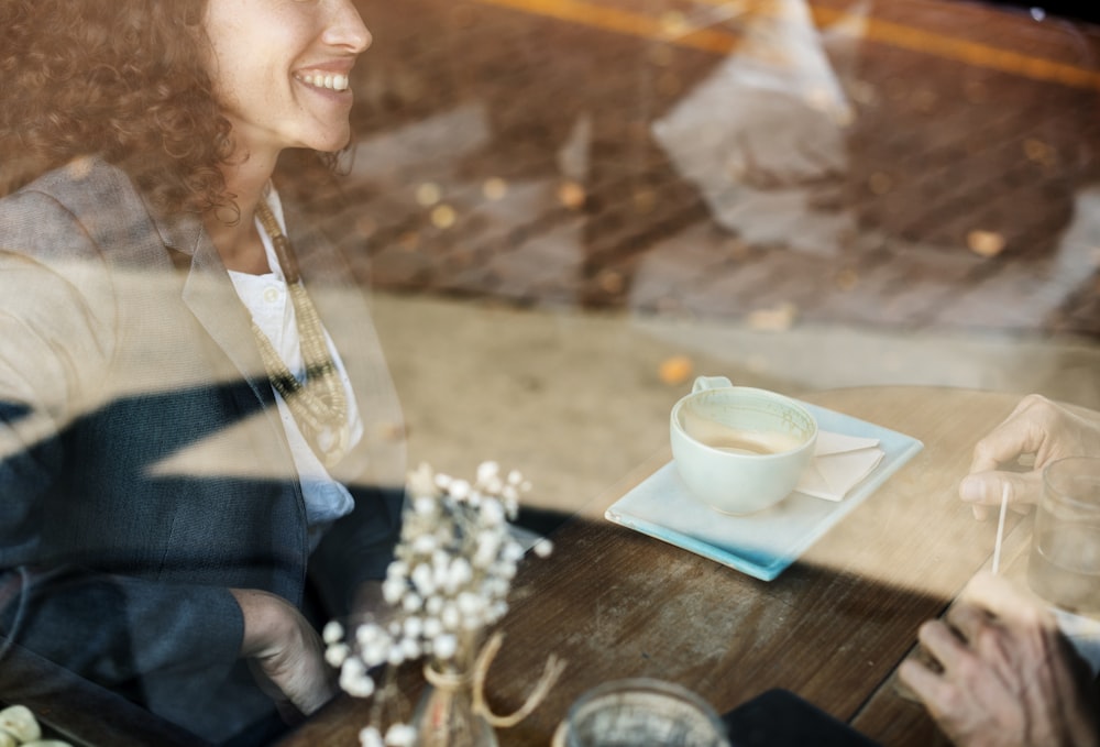 man smiling sitting in front teal teacup