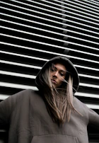 woman in hoodie standing in front of white wall