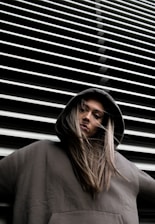 woman in hoodie standing in front of white wall