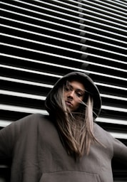 woman in hoodie standing in front of white wall
