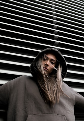 woman in hoodie standing in front of white wall