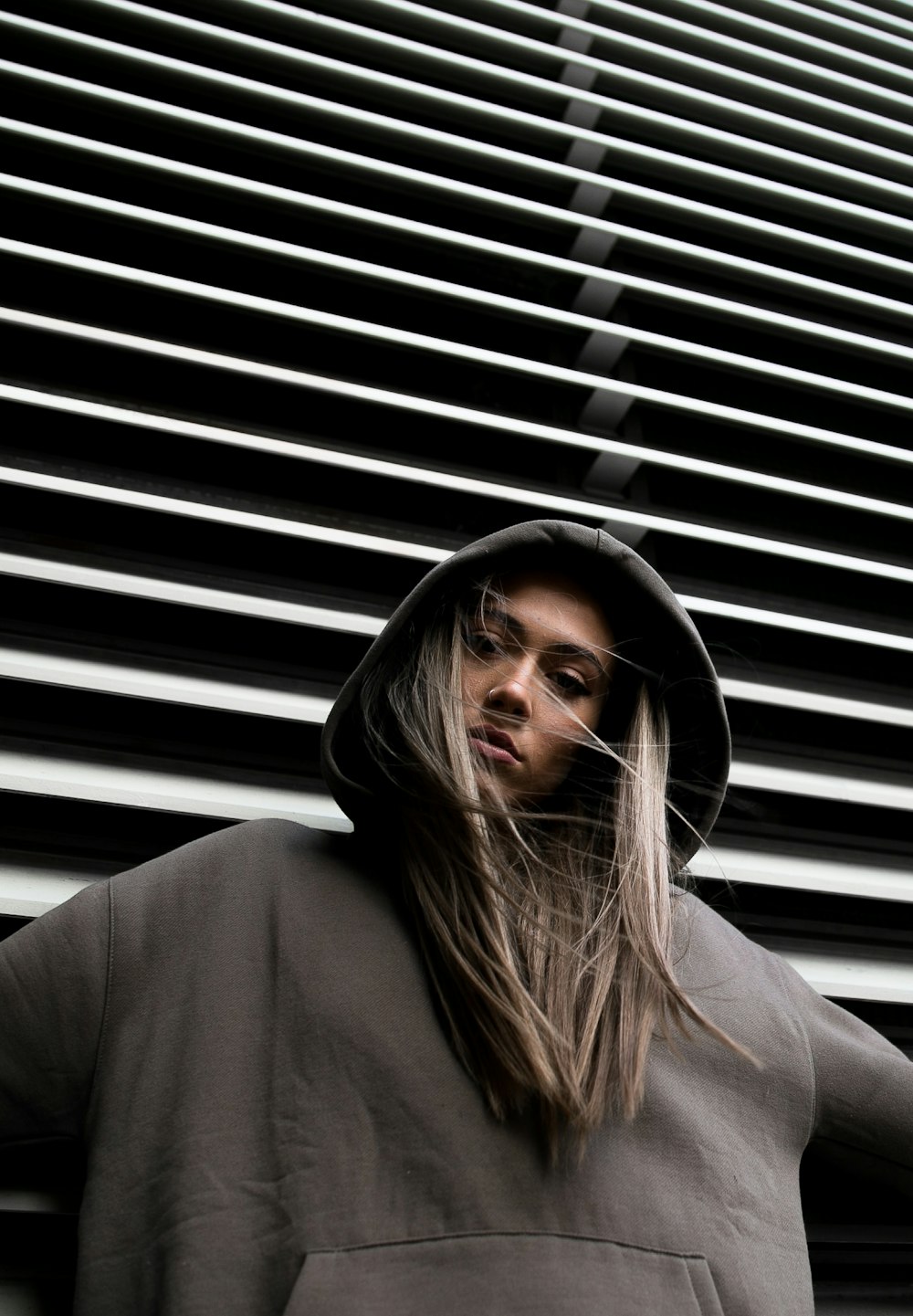 woman in hoodie standing in front of white wall