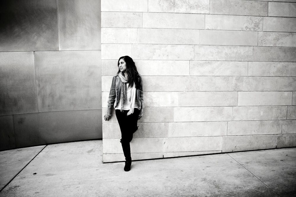 grayscale photography of woman leaning on wall