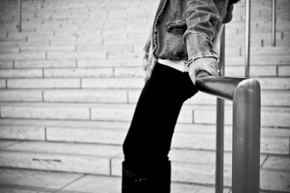 grayscale photography of person holding handrail
