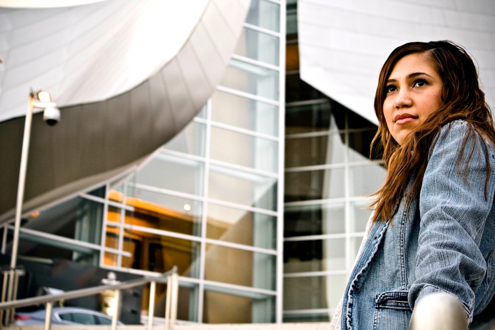 woman wearing denim jacket in front structural building