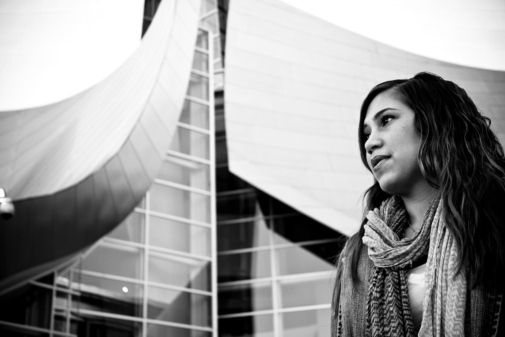 grayscale photo of woman beside building