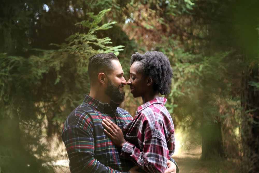 Homem e mulher vestindo camisa esportiva de botão no centro das árvores